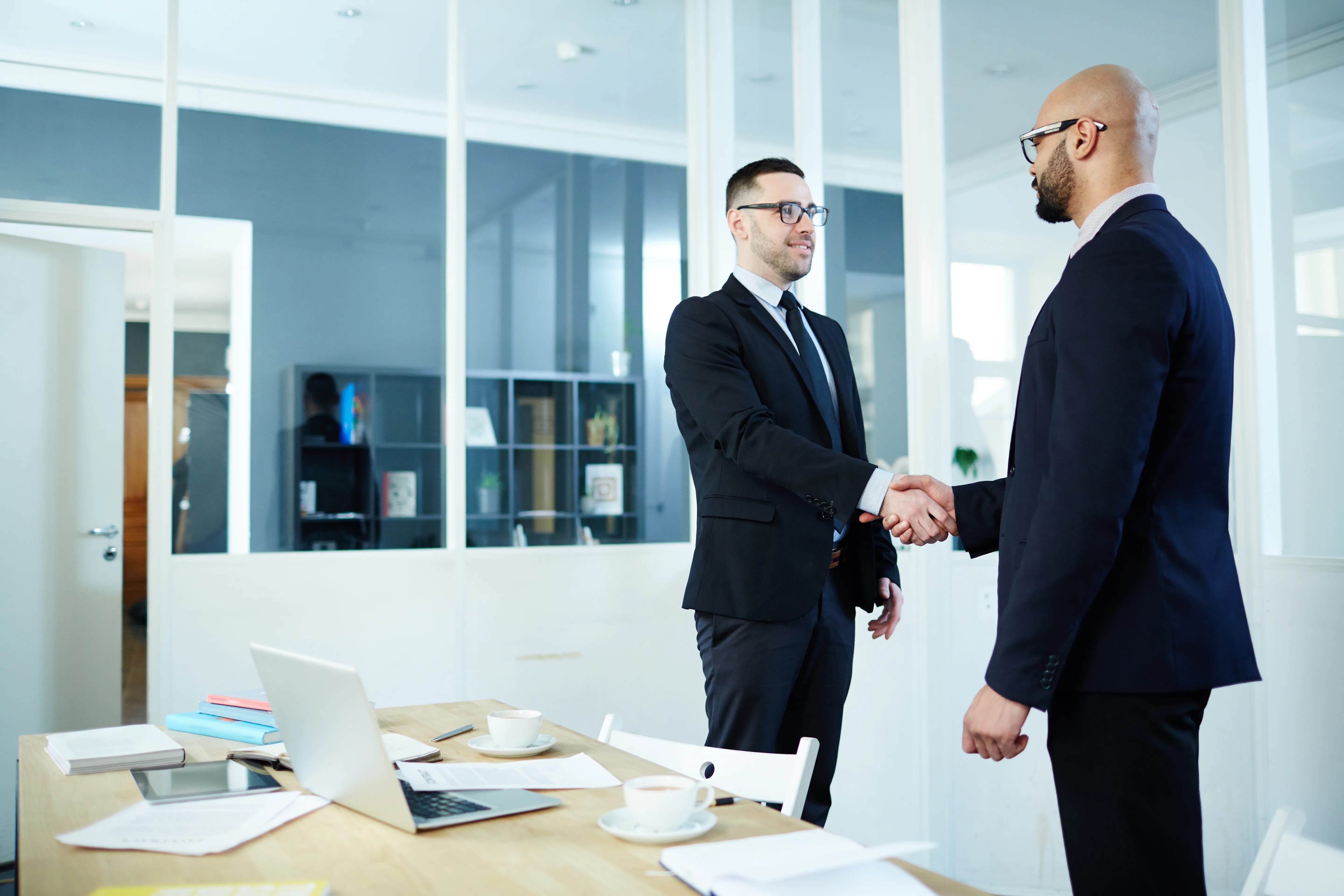 A manager shaking hands with an employee, which shows that the individual has done well in their career.